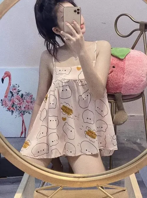 Cô nàng trong đồ ngủ sexy gợi cảm ngồi ghế mây tóc búi và che mặt bằng điện thoại