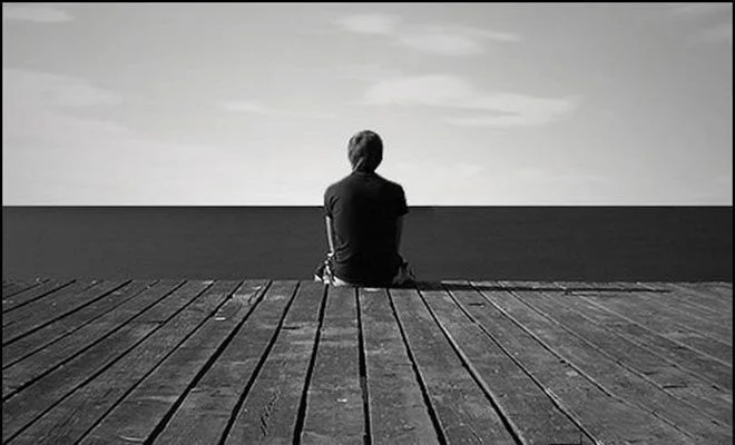 Người ngồi một mình trên sân bề gỗ nhìn về phía biển trời