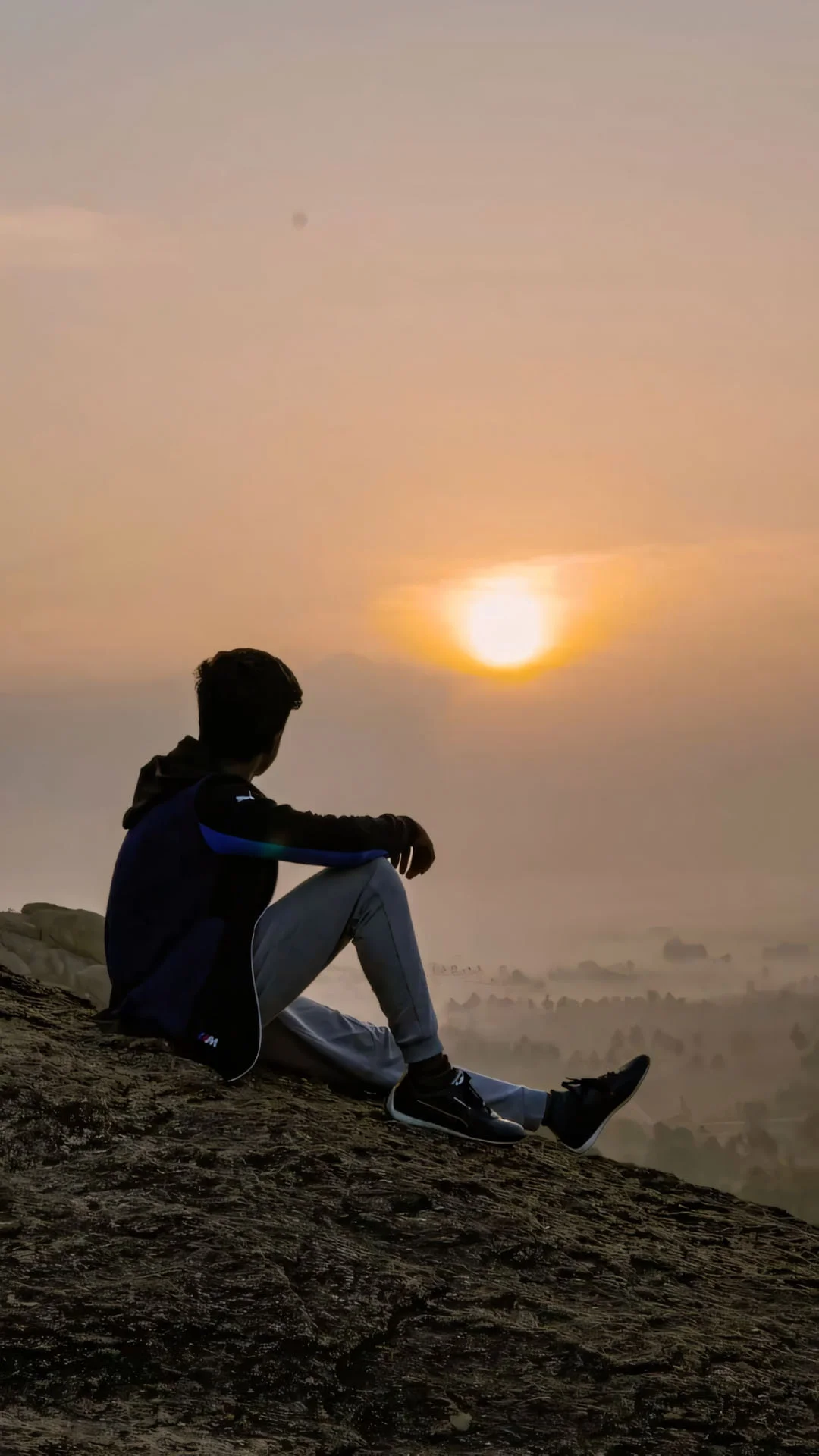 chàng trai ngồi trên đỉnh đồi ngắm hoàng hôn cô đơn
