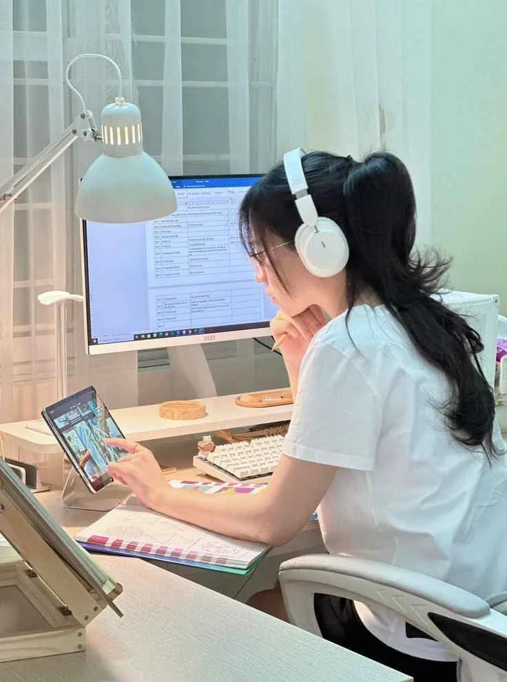 Nữ sinh học tập đeo tai nghe ngồi trước máy tính bàn