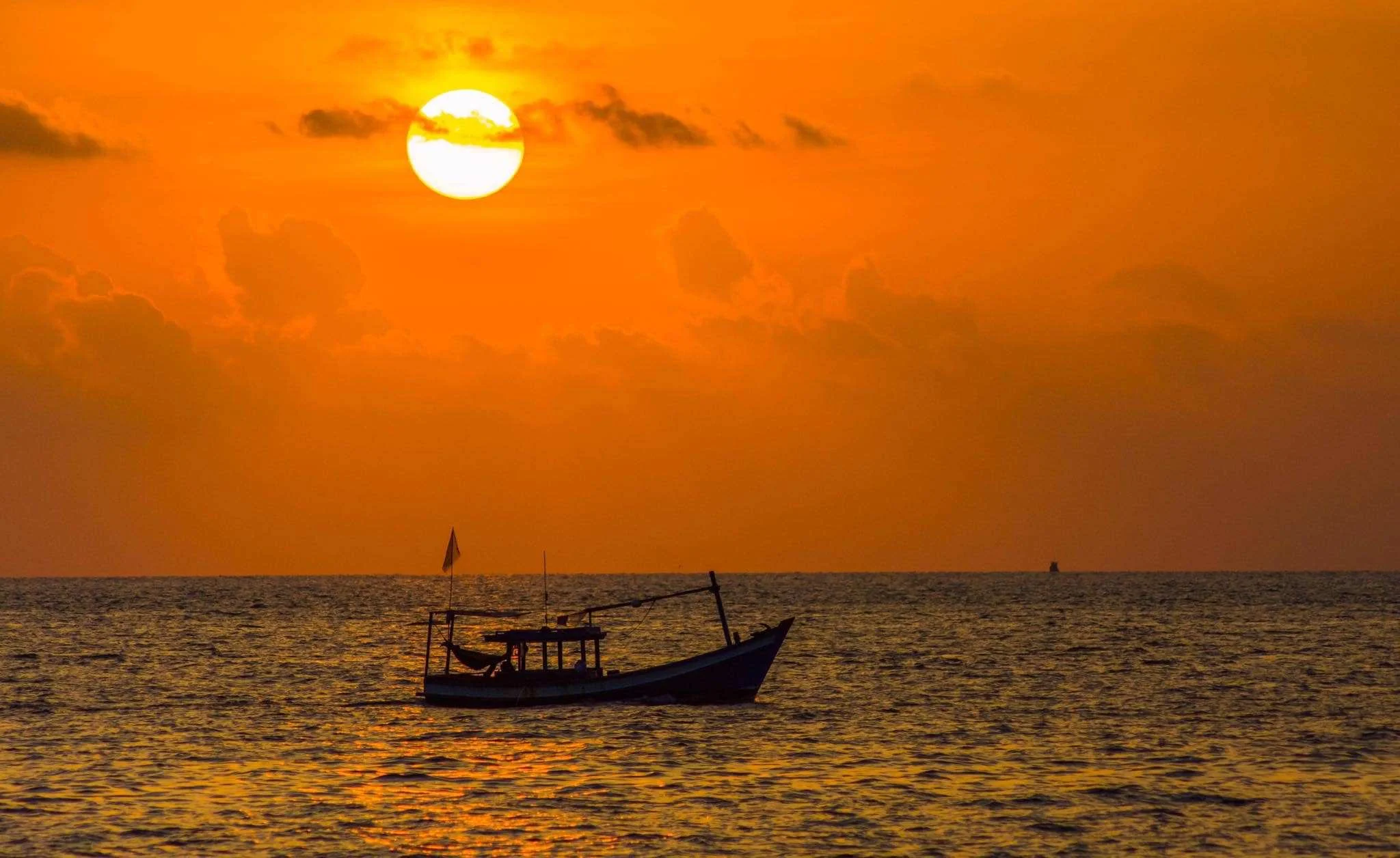Mặt trời cam trên biển hoàng hôn với chiếc thuyền đánh cá