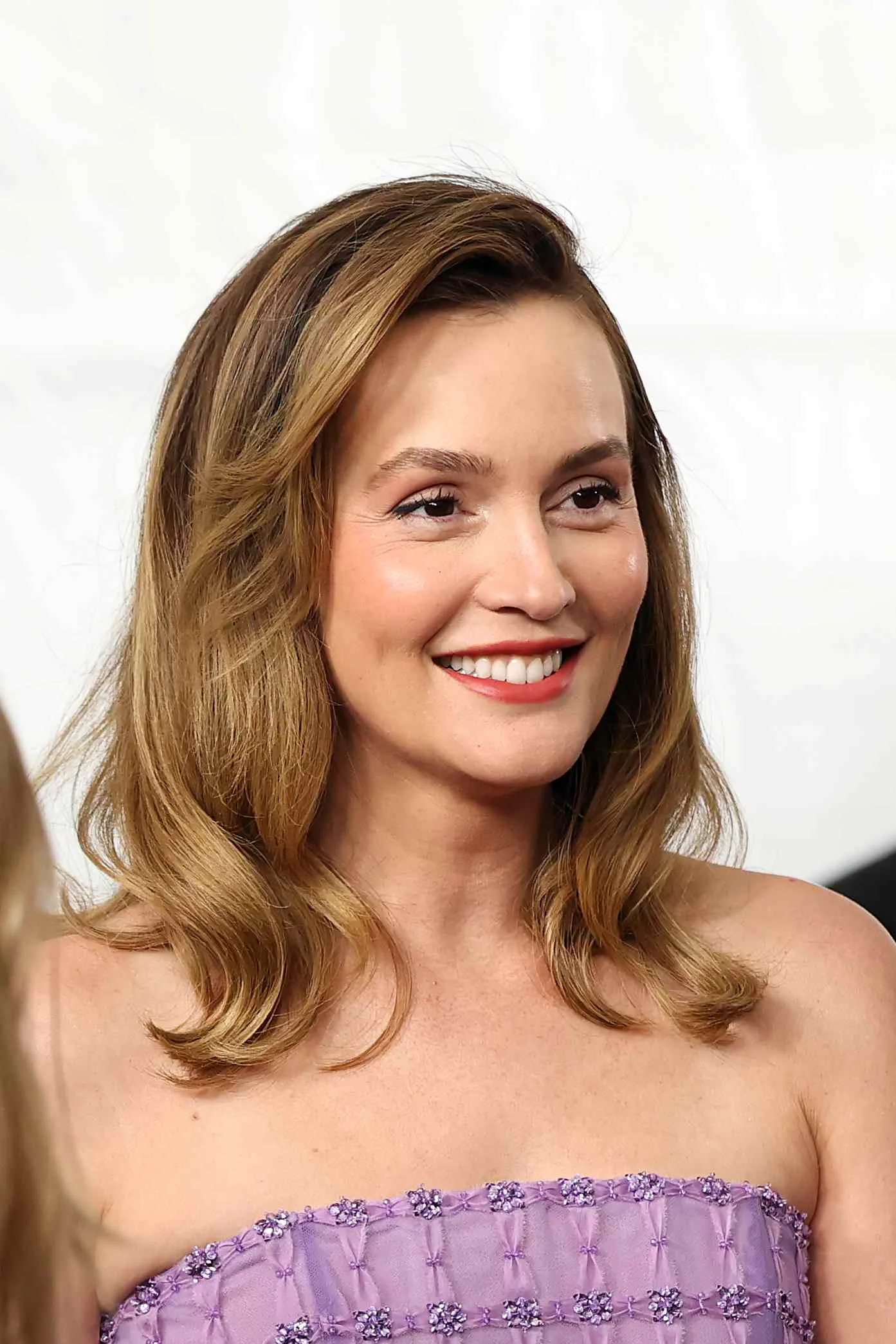 Leighton Meester smiling in a lavender strapless dress
