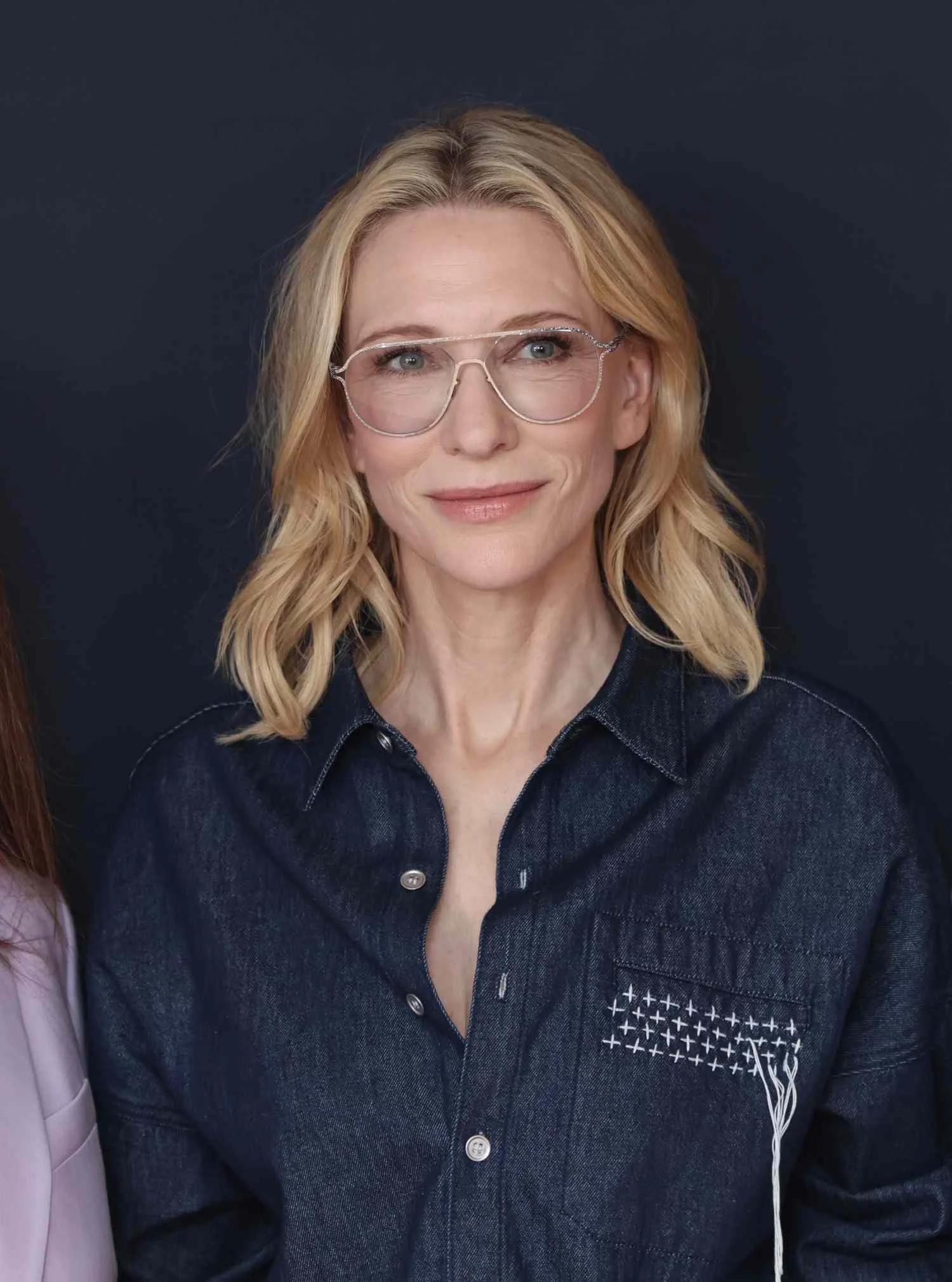 Cate Blanchett in clear, gold-frame glasses and a dark denim shirt