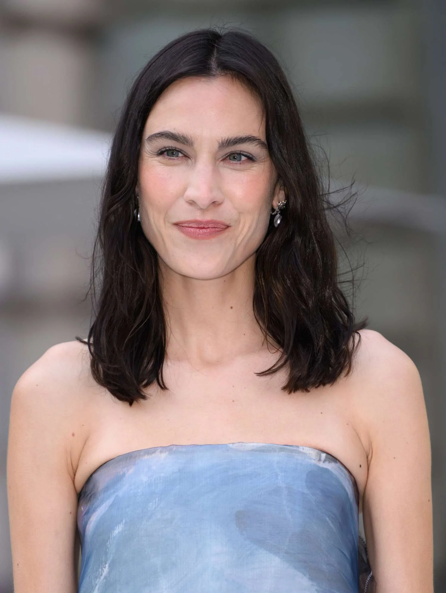Alexa Chung softly smiling in a blue strapless dress